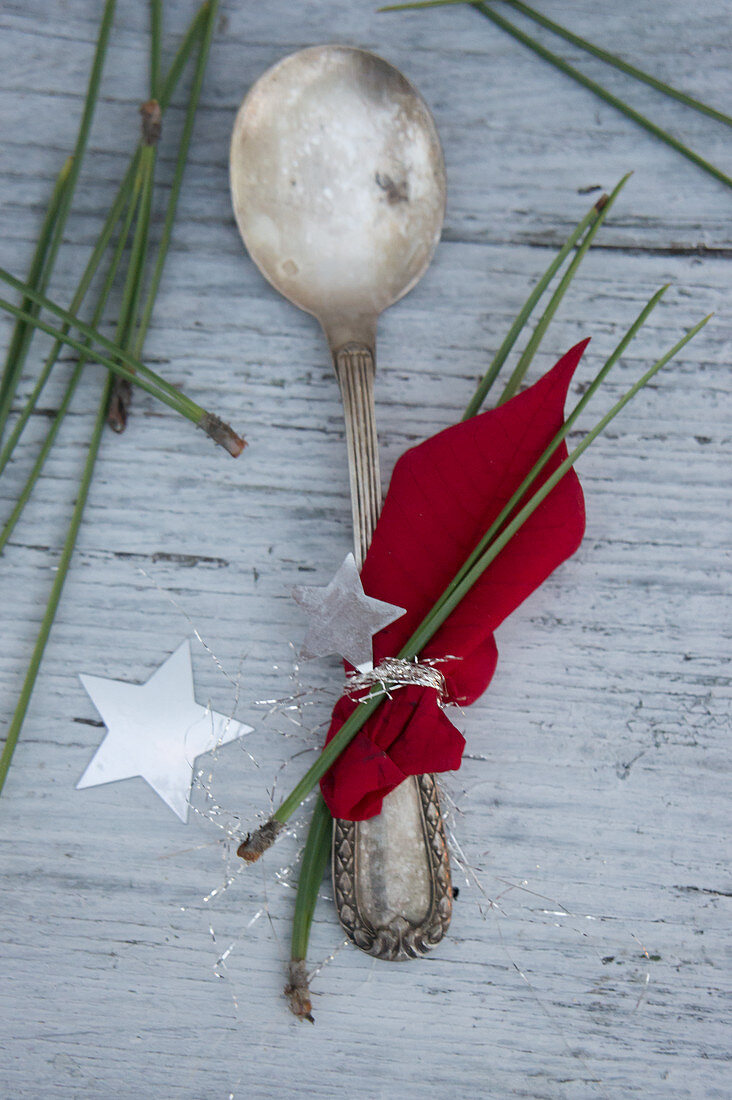 Silberlöffel mit Weihnachtsstern und Kiefernnadeln dekoriert
