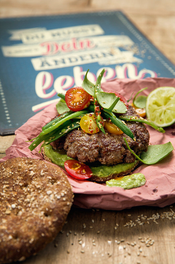 A beef burger with avocado cream, beans and salad
