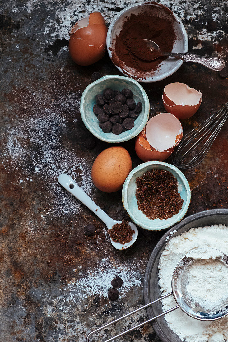 An arrangement of baking utensils: cocoa, chocolate chips, eggs, flour and sugar