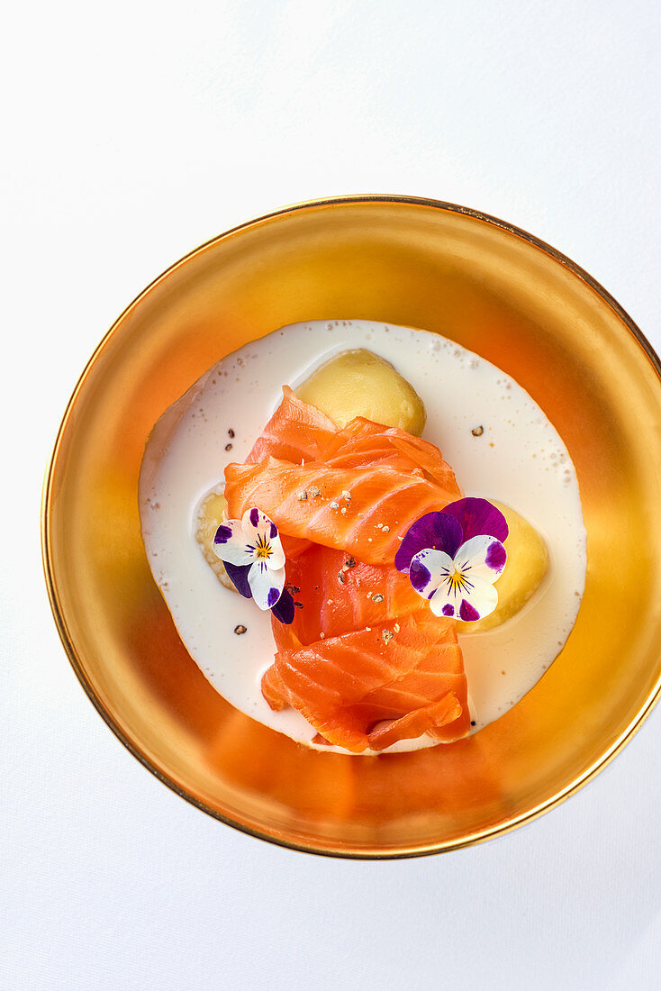 Salmon in buttermilk reduction with potatoes and edible flowers (top view)