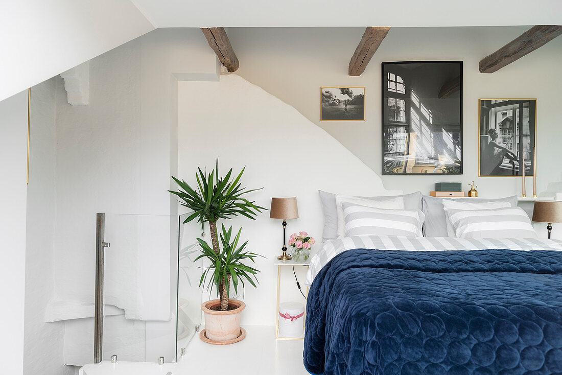 Double bed below rustic wooden beams in white bedroom