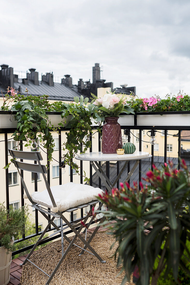 Table and chair on balcony with window boxes