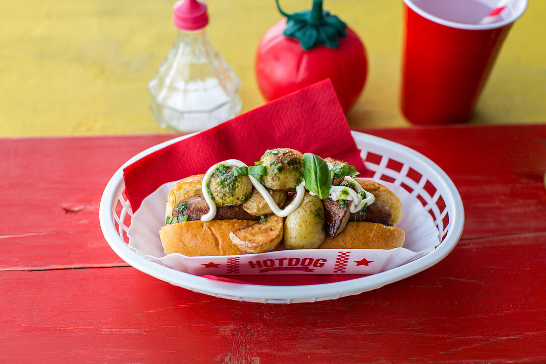 Hot Dog with pork sausage with roast potatoes, a fresh basil pesto and sour cream