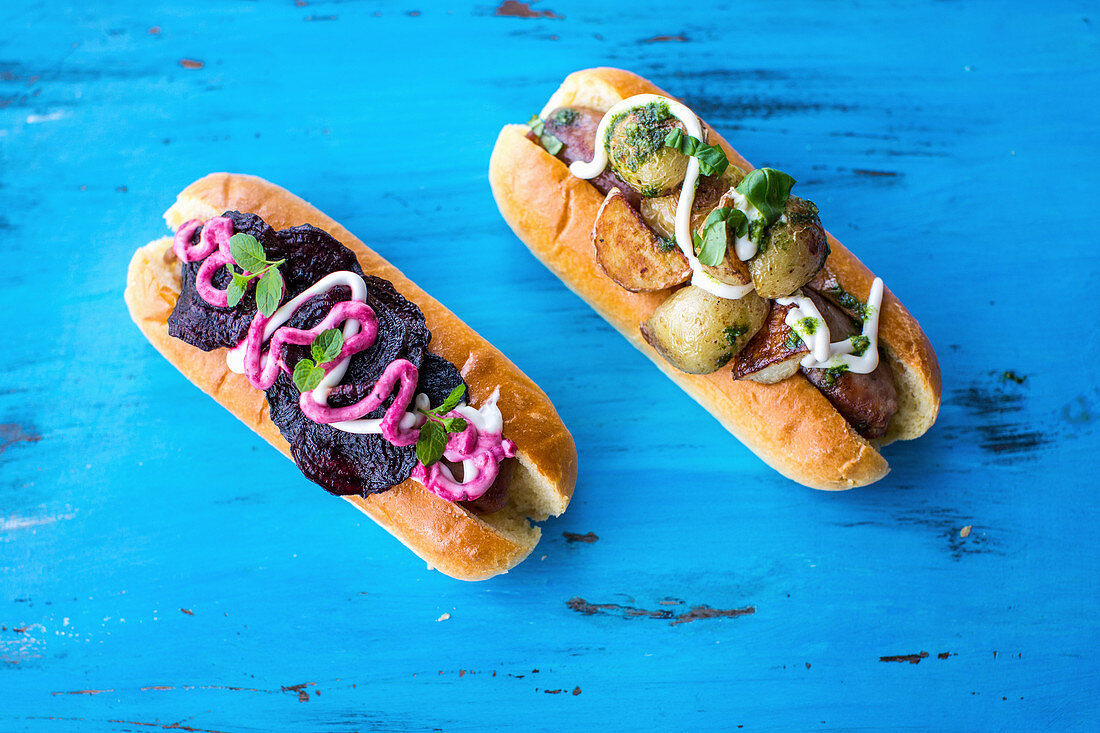 Hot Dog with pork sausage with roast potatoes, a fresh basil pesto and sour cream and with beetroot crisps, mint and beetroot sauce