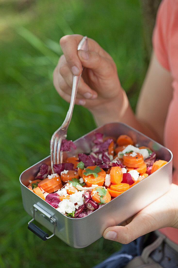 A woman eating a salad with radicchio, carrots and sheep's cheese