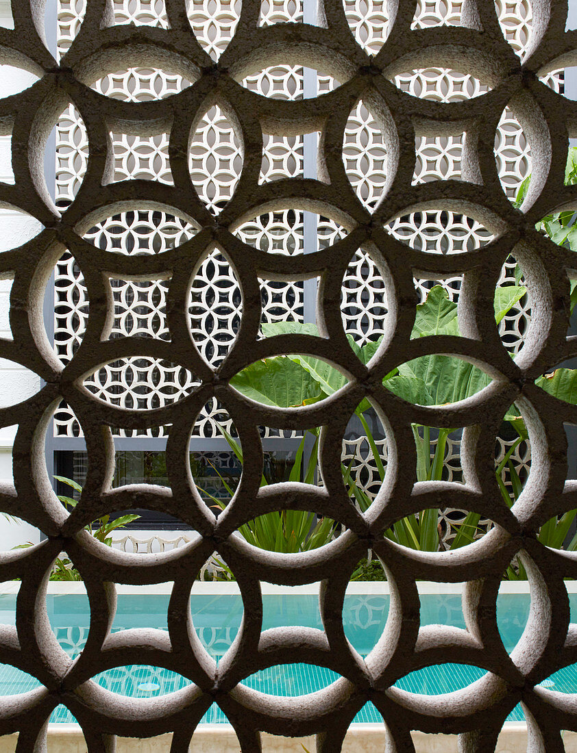 Half-open wall of ornamental perforated bricks next to pool