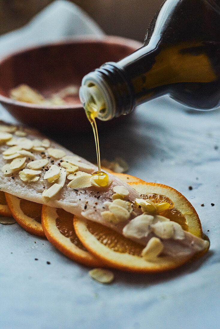 Raw fish fillet being drizzled with oil