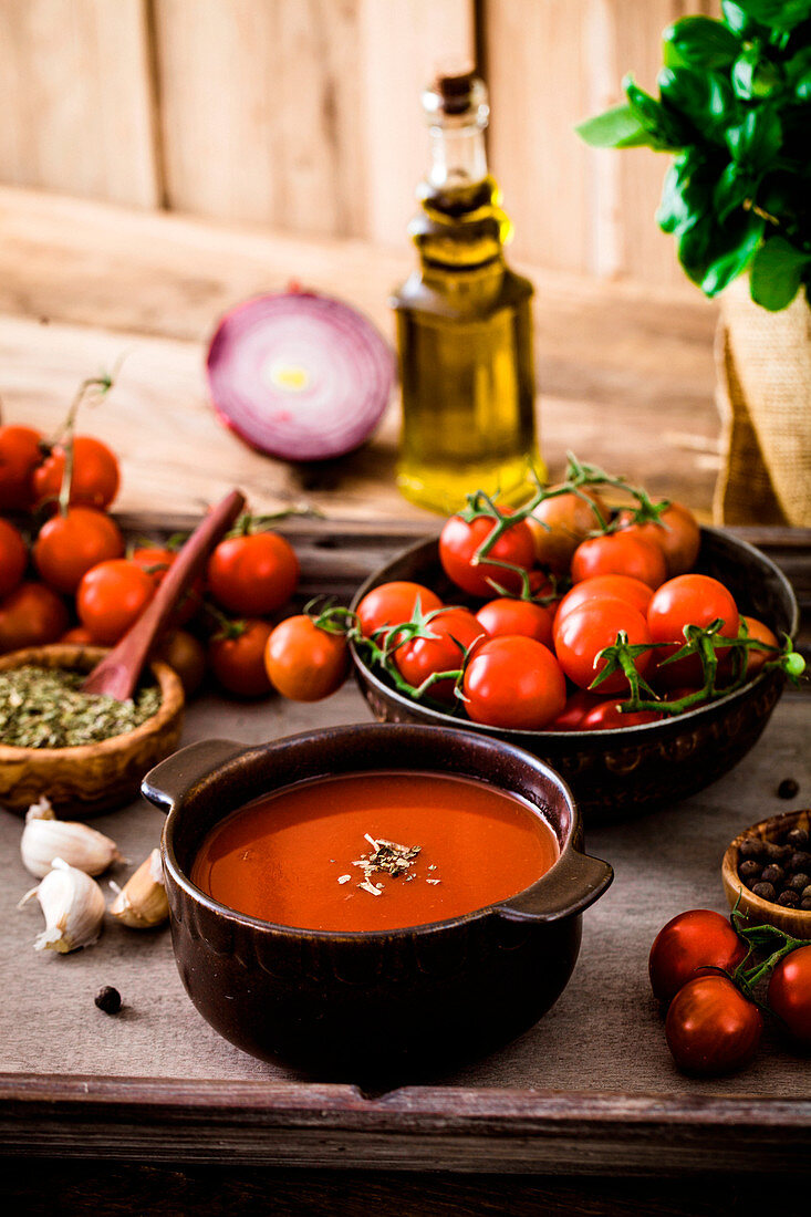 Selbstgemachte Tomatencremesuppe im Schälchen umgeben von Zutaten