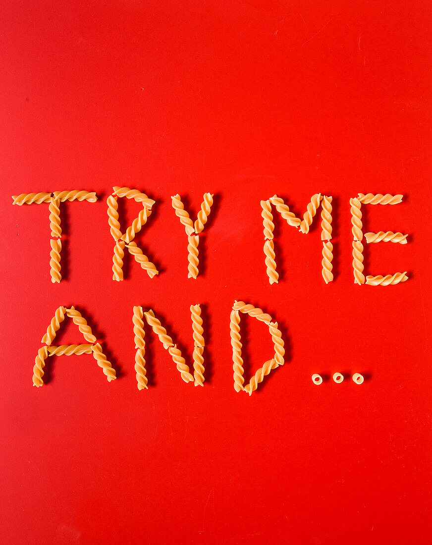 'Try me and...' spelt with fusilli pasta on a red surface