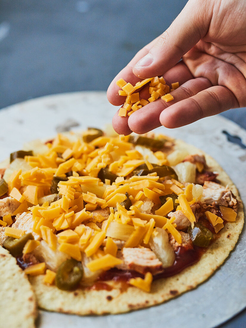 A quesadilla being sprinkled with cheese