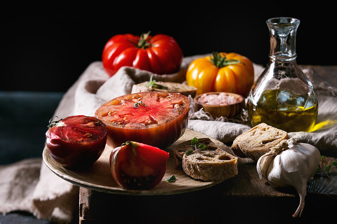 Red and yellow organic tomatoes with olive oil, garlic, salt and bread for salad or bruschetta