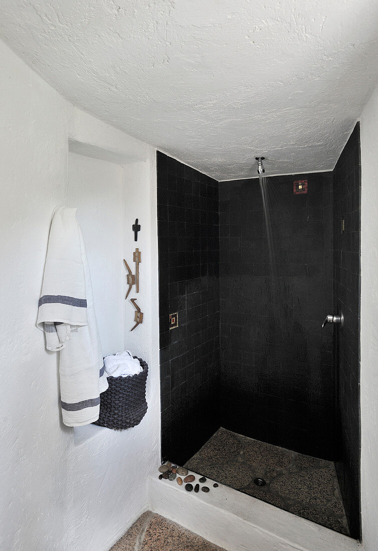 Duschbereich mit schwarzen Fliesen in weißem Bad