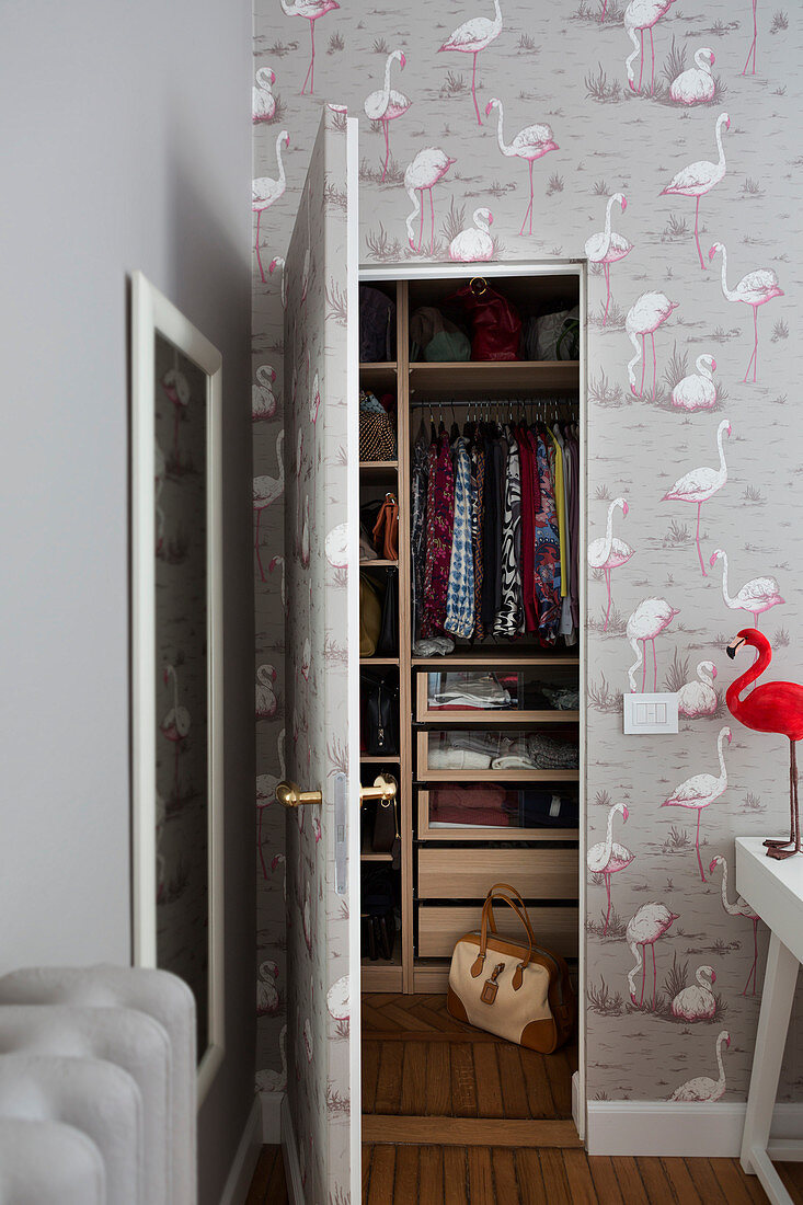 Flamingo-patterned wallpaper on wall and door into walk-in wardrobe