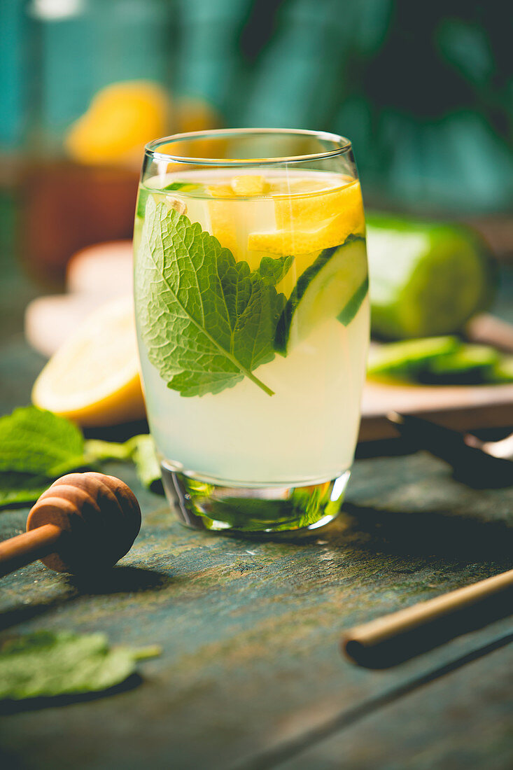 Fresh cool lemon cucumber mint and honey infused water, cocktail, detox drink, lemonade in a glass on wooden background