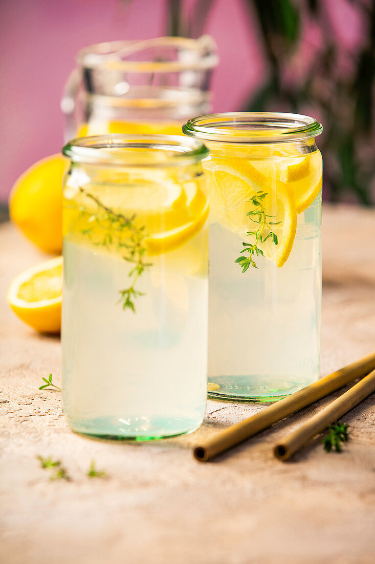 Lemonade with lemons and thyme on rustic table