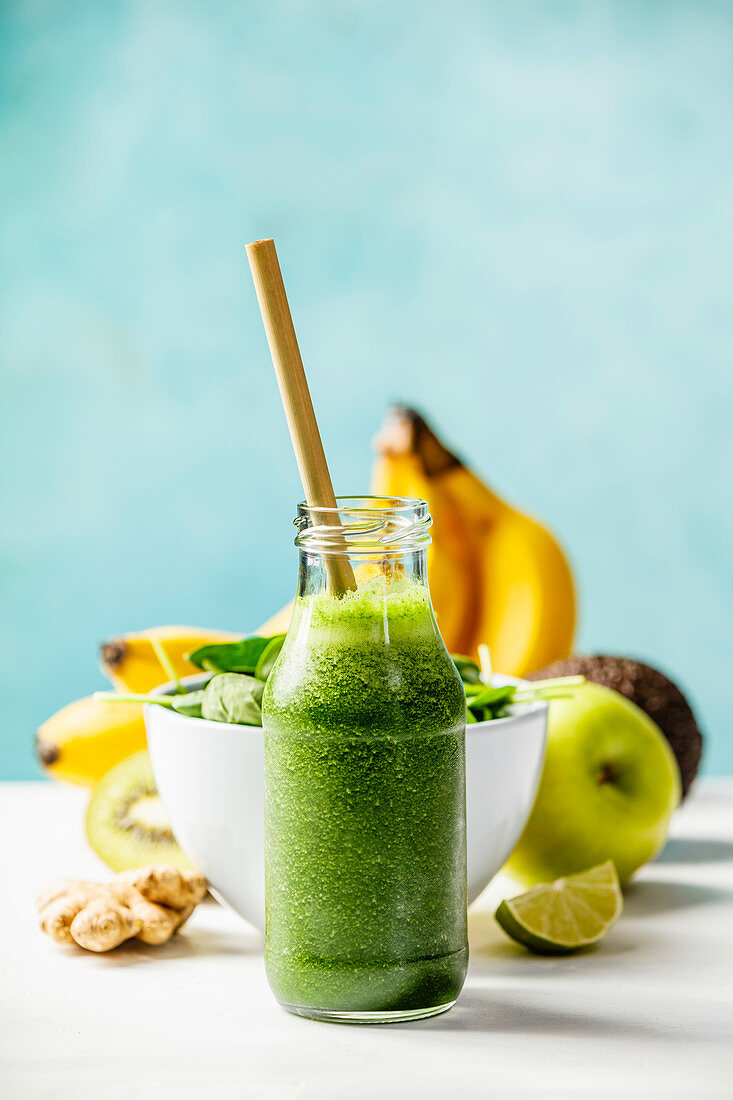 Green smoothie and ingredients on the table against the wall