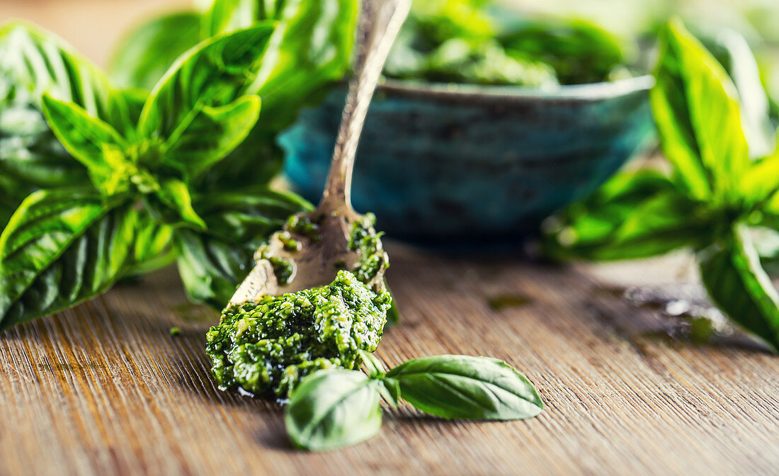 Fresh basil leaves and pesto on wooden table