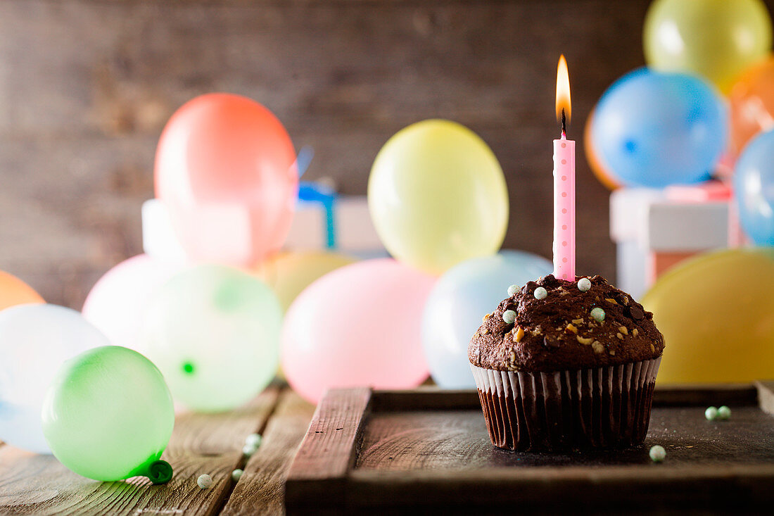 Schokoladen-Cupcake mit brennender Kerze zum Geburtstag