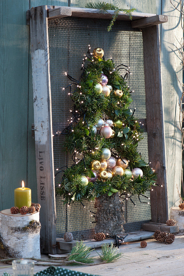 Stylized fir tree made of branches, balls and fairy lights