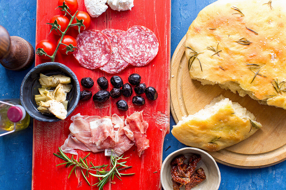 Antipasti: Focaccia mit Rosmarin, Finocchiona (Fenchelsalami), Tomaten, Artischocken, schwarze Oliven und Schinken