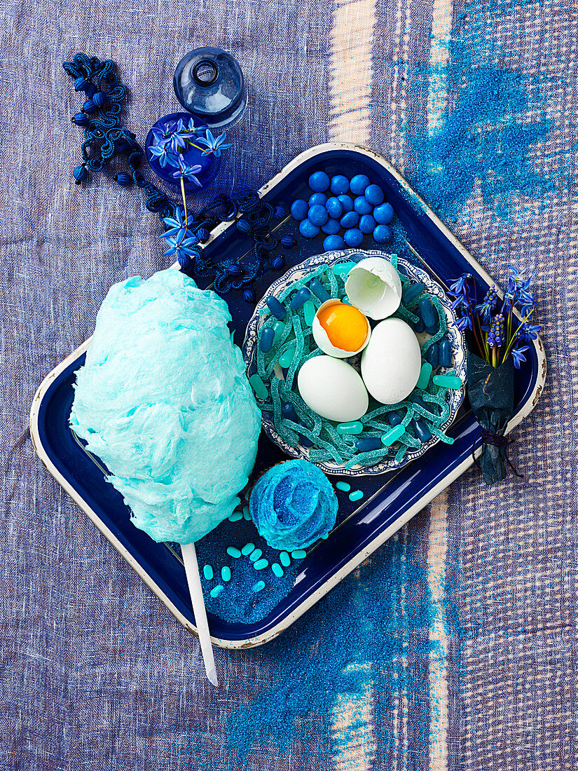 Still life in blue with cotton candy, cupcake and eggs
