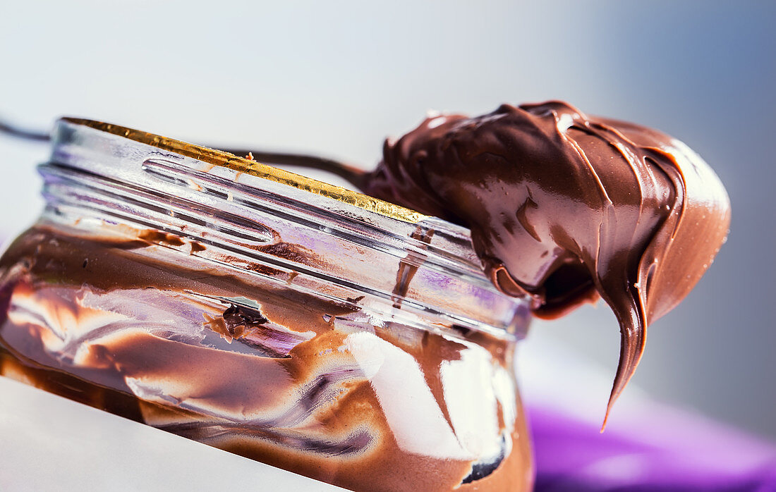 Löffel und Glas mit Schokoladen-Haselnuss-Aufstrich