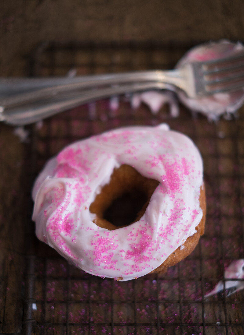 Donut dekoriert mit rosafarbenem Frosting und pinkfarbenem Zucker