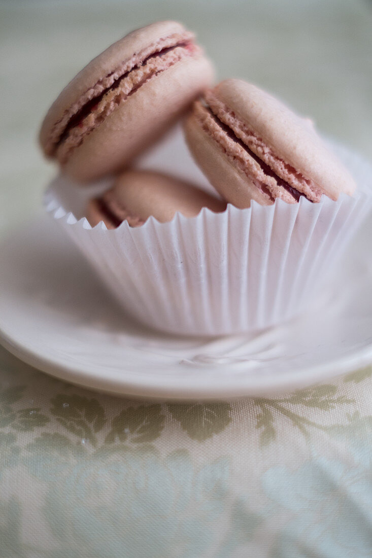 Three pink macarons in a paper cup