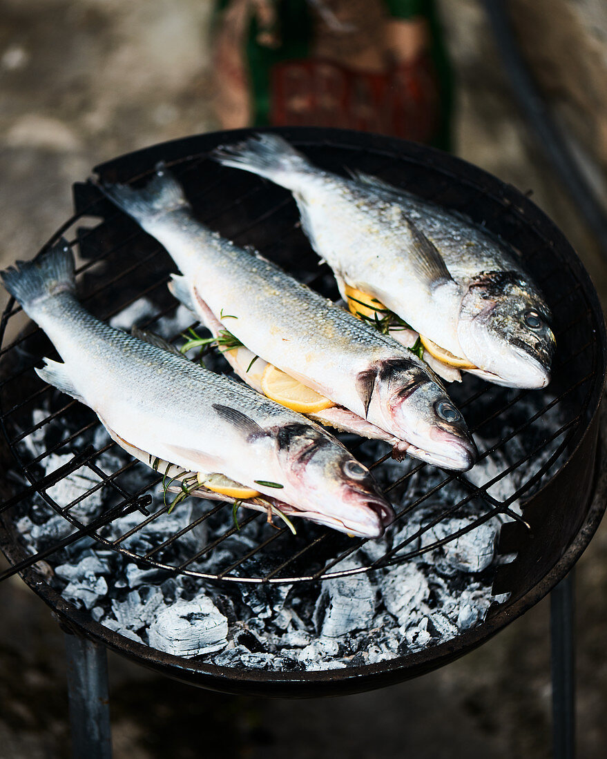 Fresh fish on a barbecue, garnished with lemon and rosemary