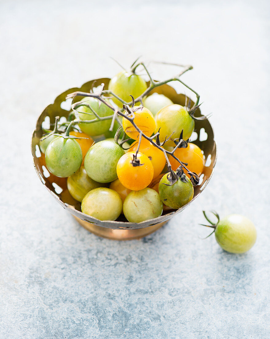 Green and yellow cherry tomatoes in a small bowl