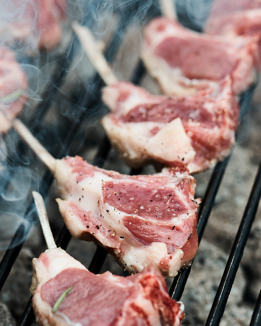 Fresh lamb racks layed on a barbecue to cook