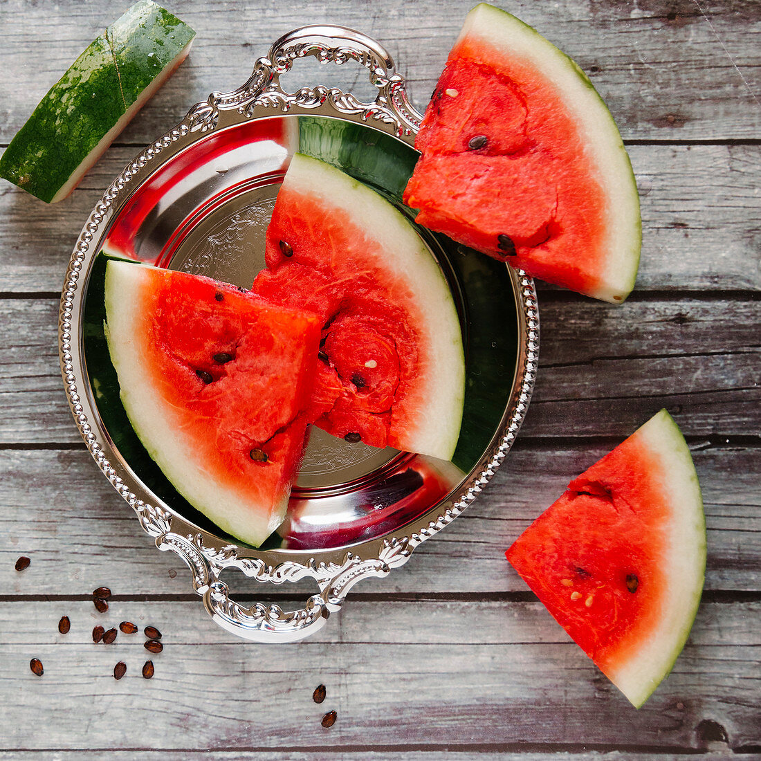 Watermelon slices on a silver tray and a wooden background