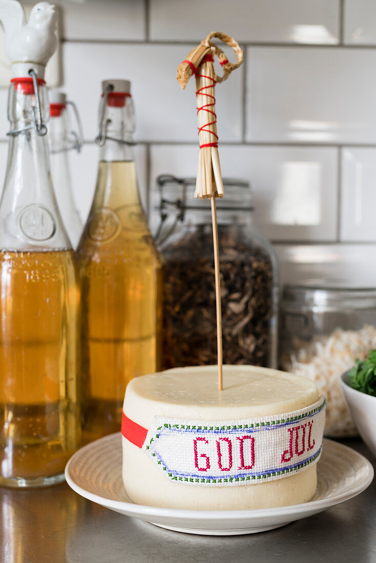 Ribbon embroidered with Christmas greeting tied around cheese wheel