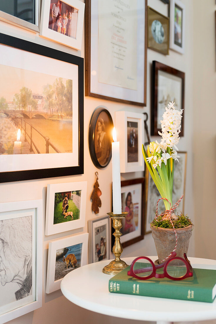Hyacinths, candles, book and spectacles on side table next to framed photos