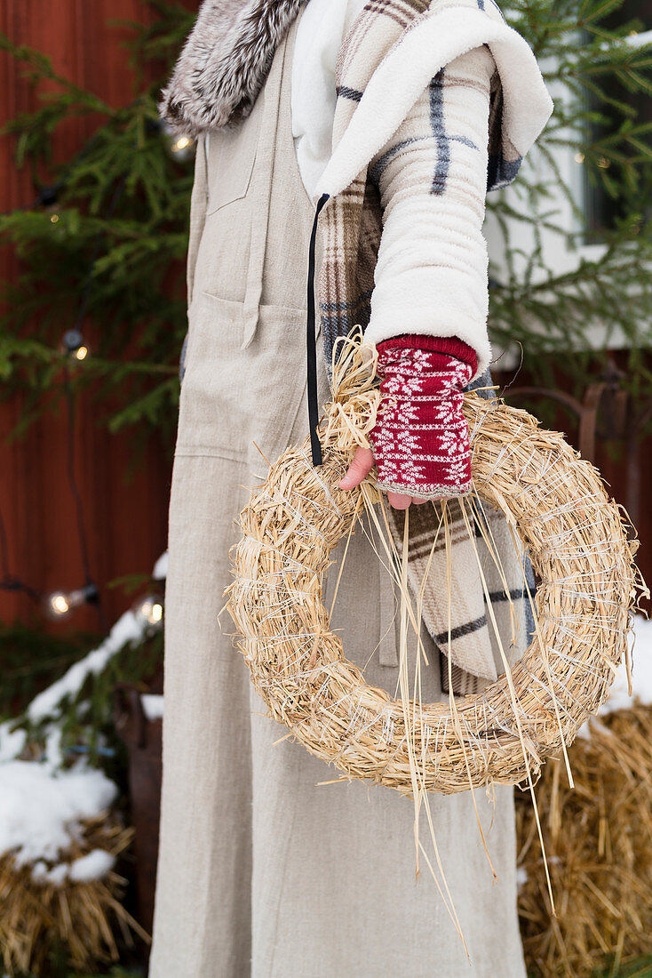 Woman dressed for winter holding straw wreath