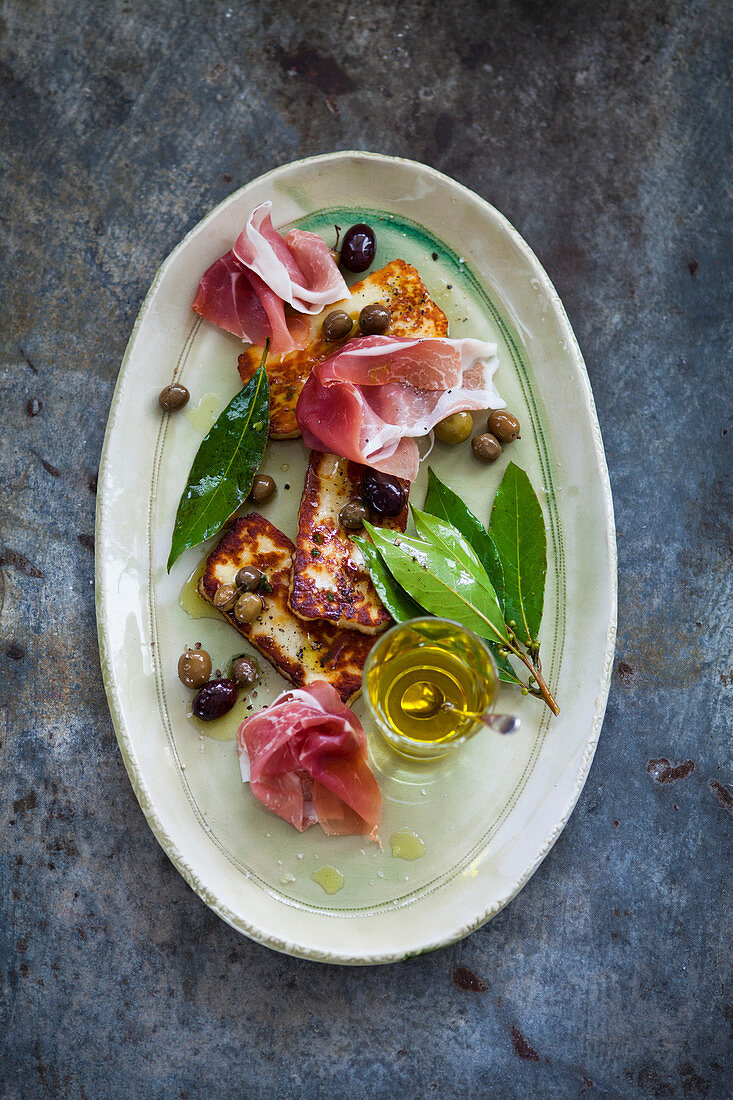 Halloumi with prosciutto, olives, olive oil and bay leaves