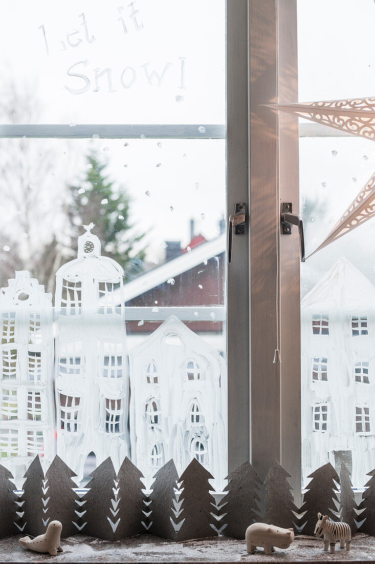 Aufs Fenster gemalte Häuser und Bäume aus Papier