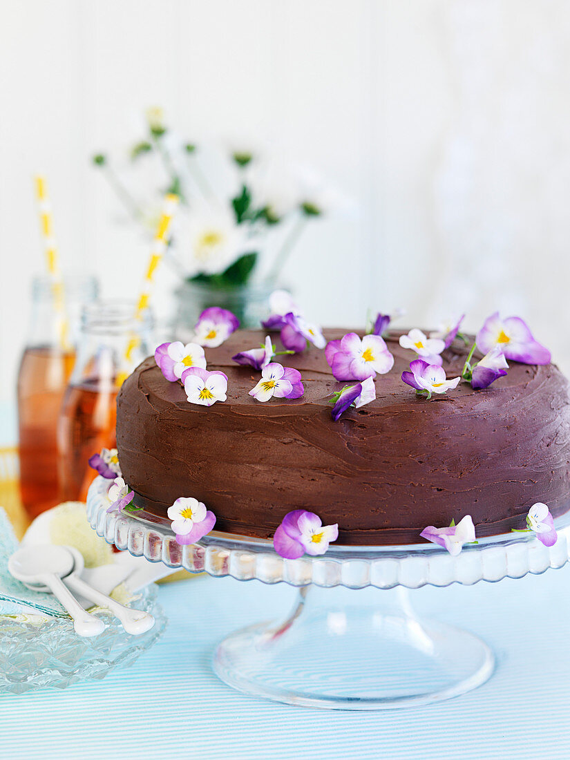A chocolate cake decorated with horned violet flowers