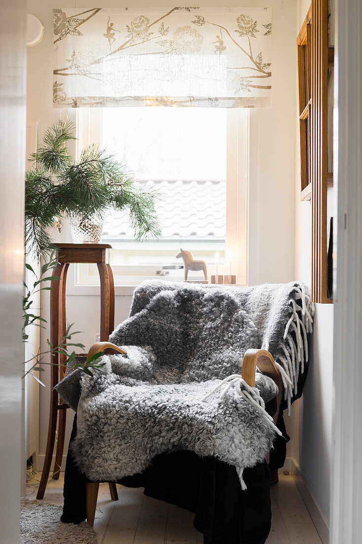 Grey sheepskin blanket on armchair in front of window