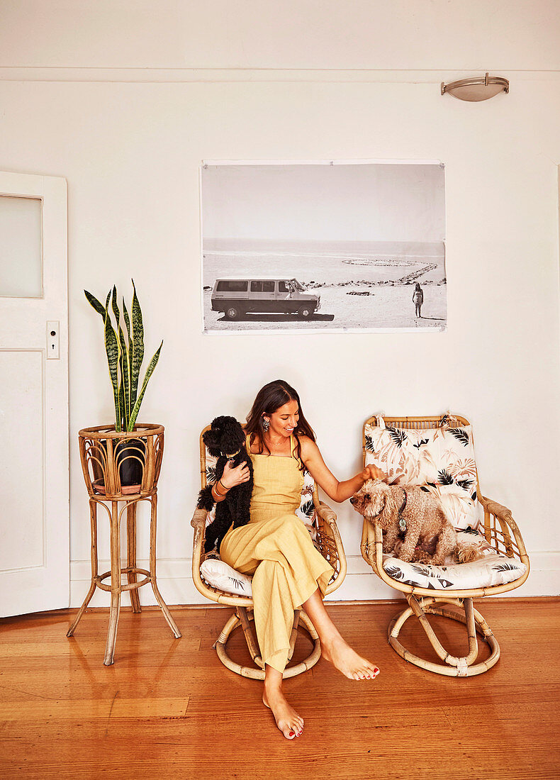 Young woman with two dogs next to houseplant