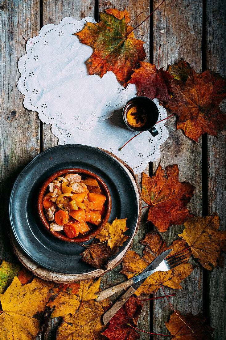 Chicken curry with pumpkin, a cup of tea and autumn leaves