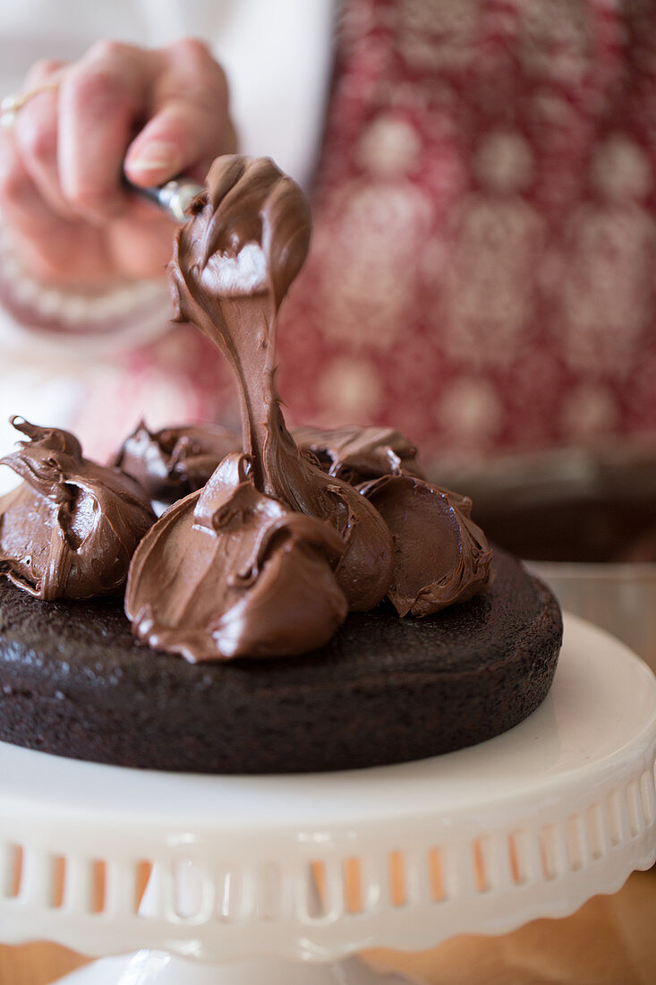 A cake being made: chocolate cream being spread onto a cake base