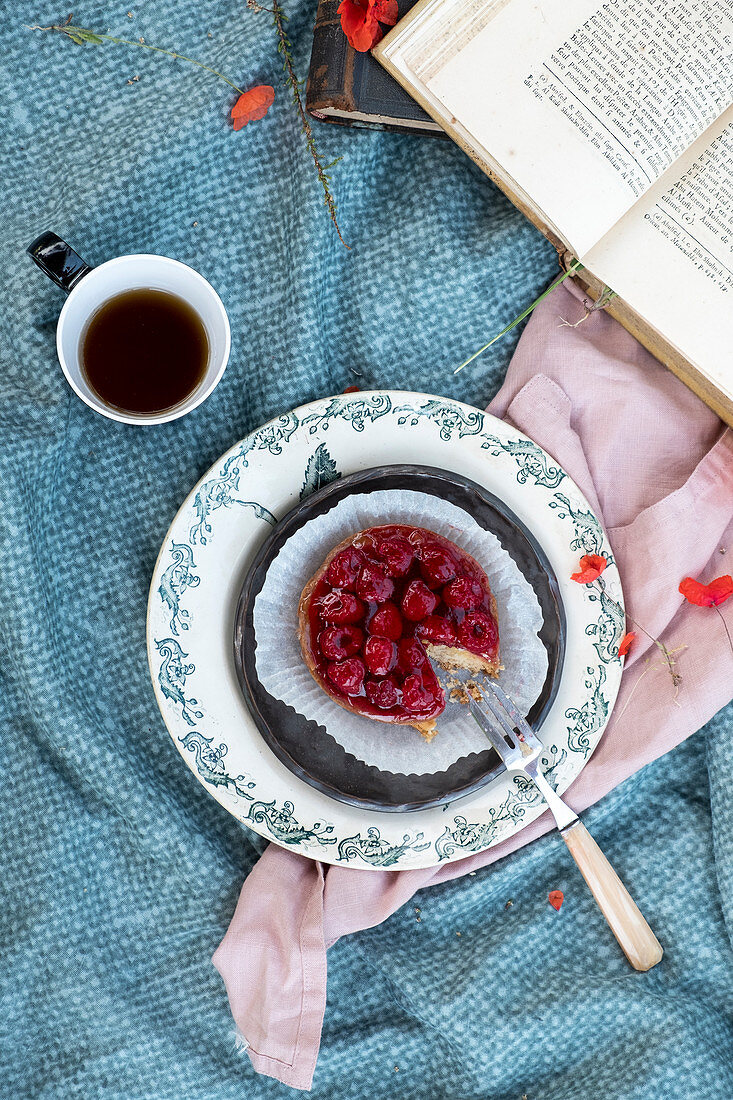 Raspberries cake with a cupo of tea and a book