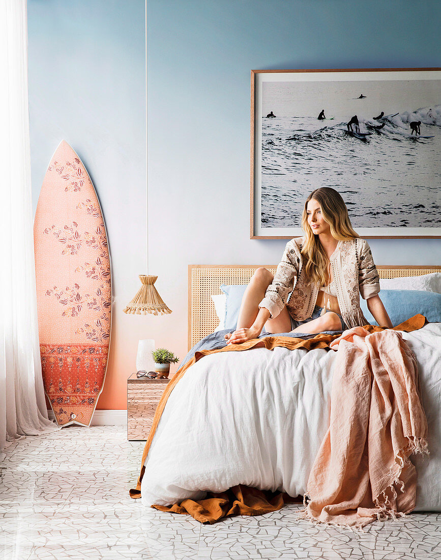 Young woman sitting on bed in bedroom in beach look