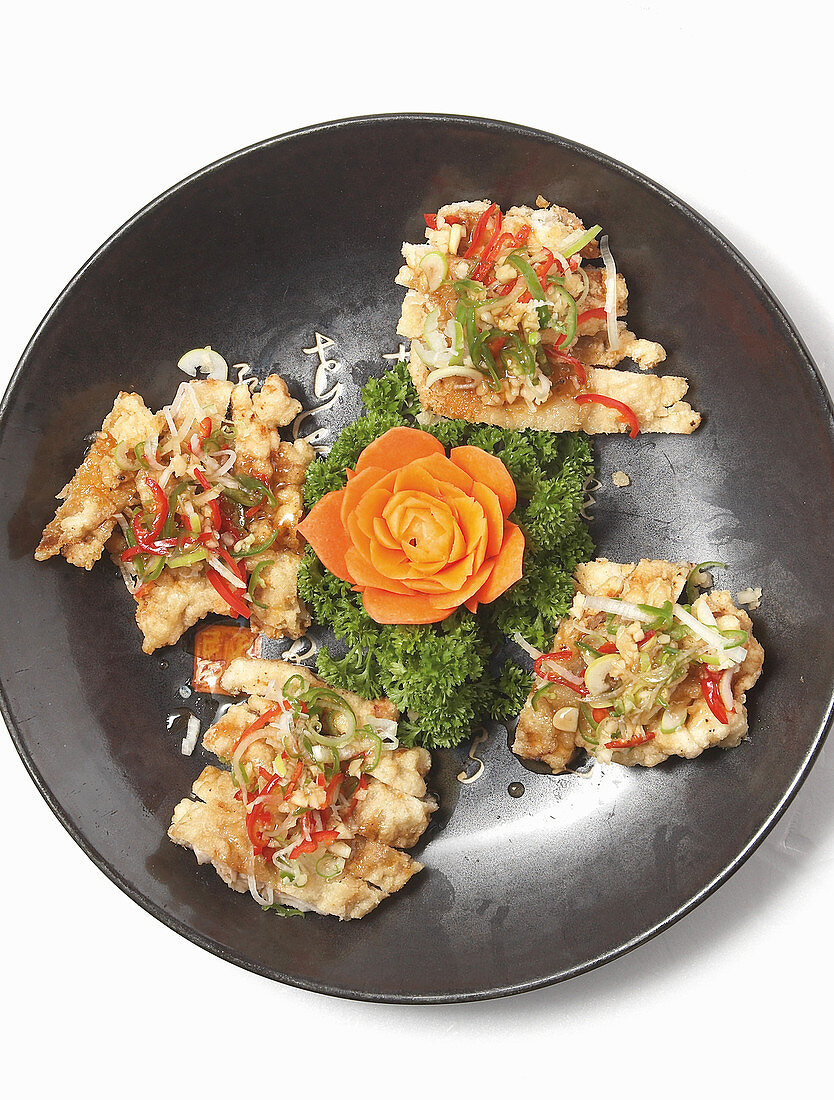 Fish cutlets garnished with parsley and a carved carrot flower (Asia)