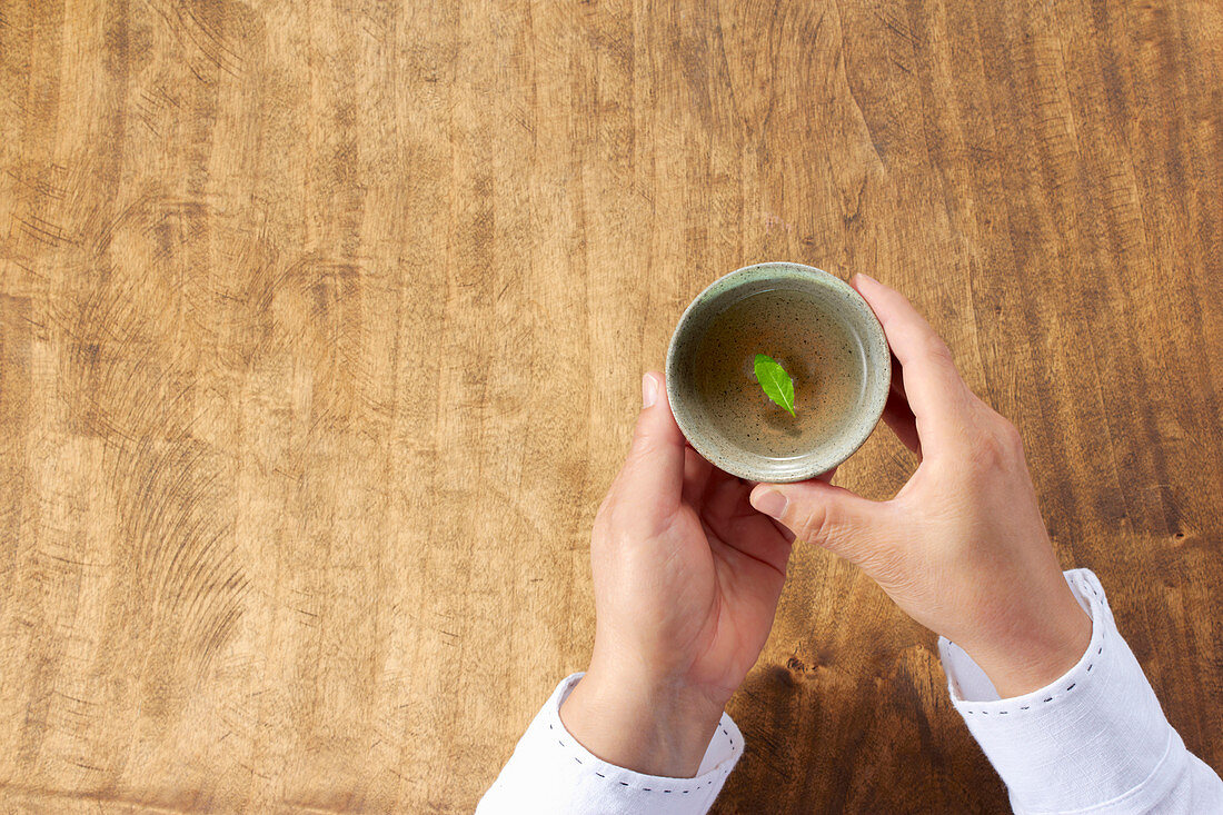 A woman holding a cup of green tea