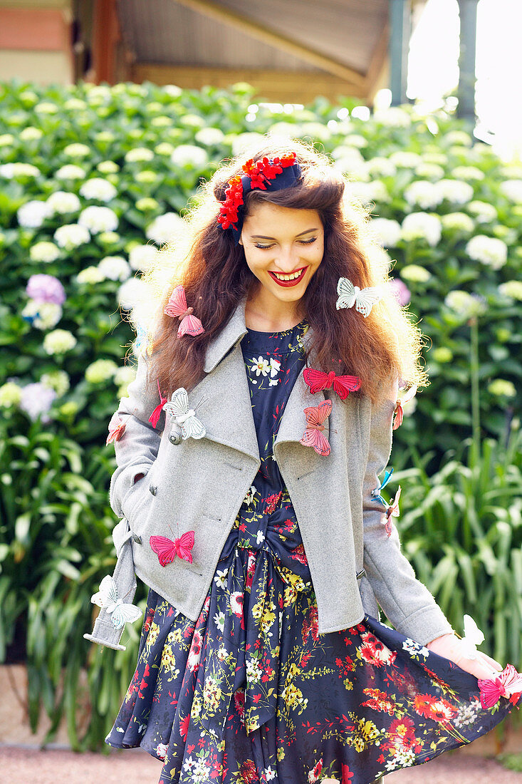 A dark-haired woman wearing a summer dress and a jacket decorated with butterflies