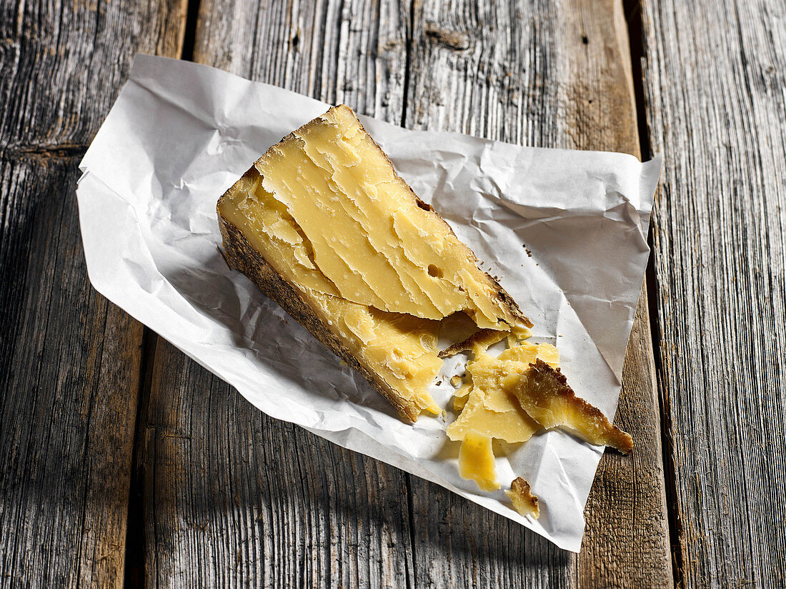 A slice of alpine cheese on a weathered wooden board