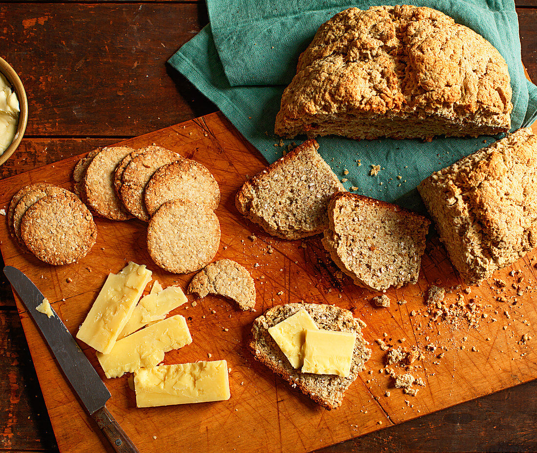 Sodabrot und Sodacracker mit Butter und Käse auf Holzschneidebrett