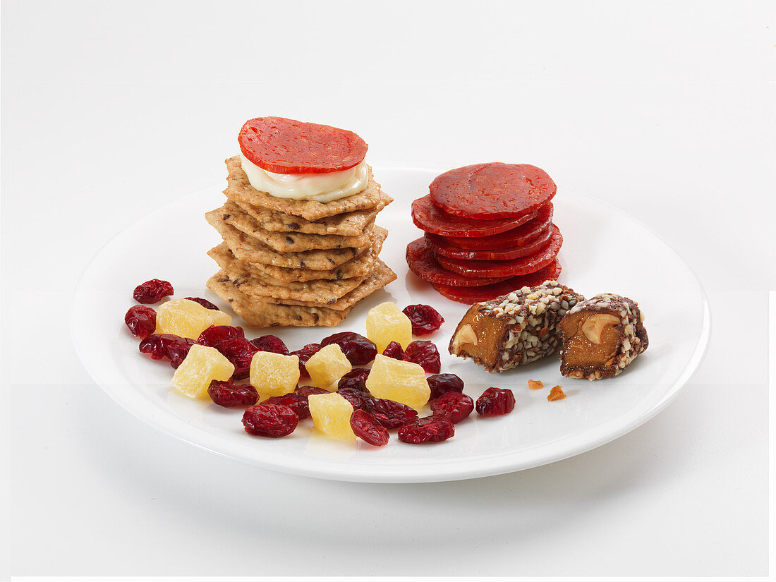 Süsse und pikante Snacks auf Teller: Cracker, Wurst, Trockenfrüchte und Konfekt
